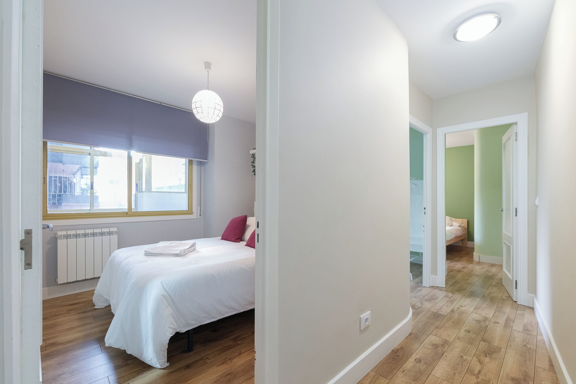 Una camera da letto con un letto, un termosifone, una finestra vista e una lampada a sospensione.