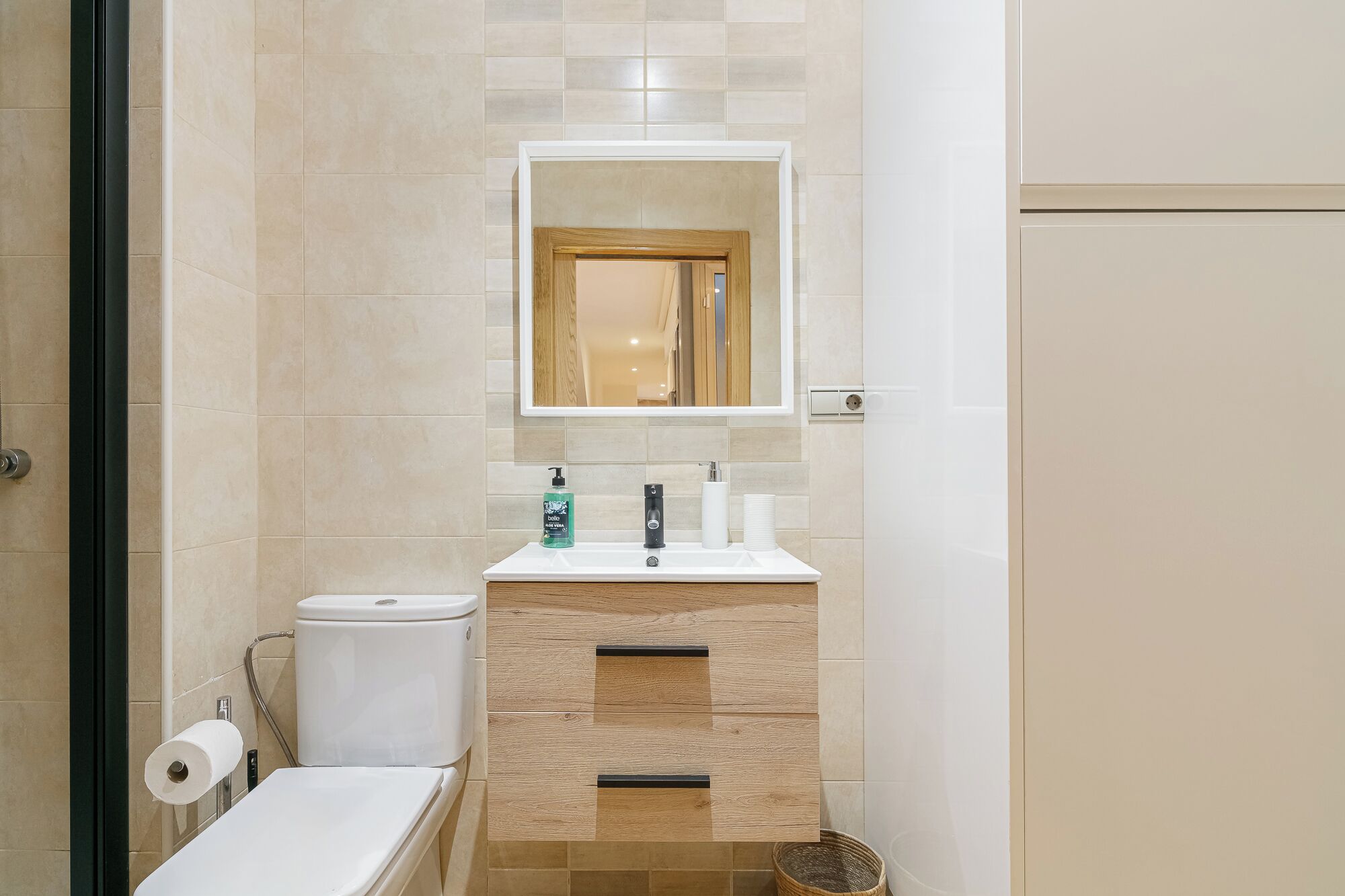 Un baño con inodoro, lavabo, espejo y zona de ducha.
