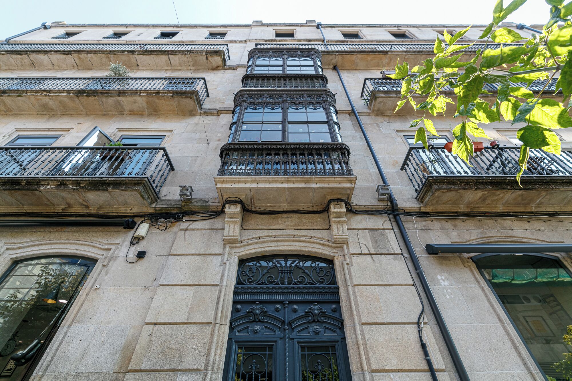 A building with multiple balconies, ornate iron railings, and a large central door with intricate designs.