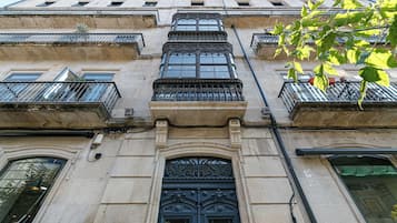 A building with multiple balconies, ornate iron railings, and a large central door with intricate designs.