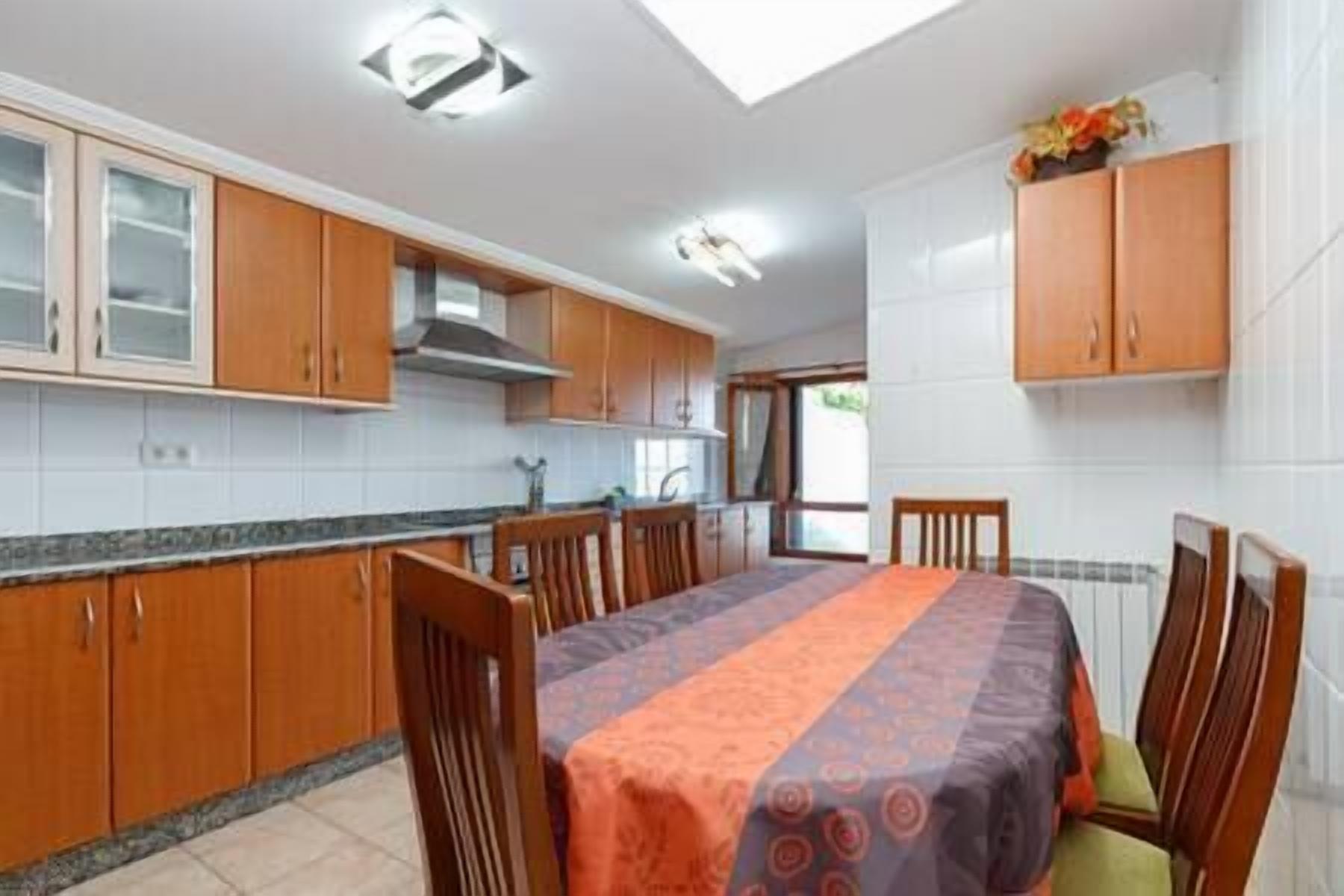 Uma cozinha com armários de madeira, uma mesa de jantar com cadeiras e uma janela que oferece luz natural.