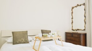 A neatly made bed with rolled towels, a tray with toiletries, and a mirror on a dresser. - Easylife - Modern and central apt in Porta Romana (Milano)