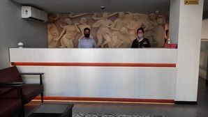 A reception area with a marble wall, a reception desk, and a seating area with a patterned rug. - Hotel Vemara (Panaji)