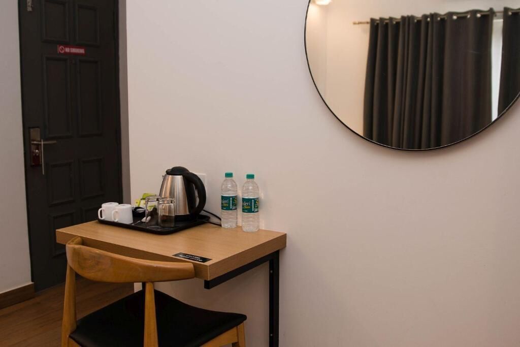 Une petite table en bois, une chaise noire, une machine à café, deux bouteilles d’eau et une tasse.