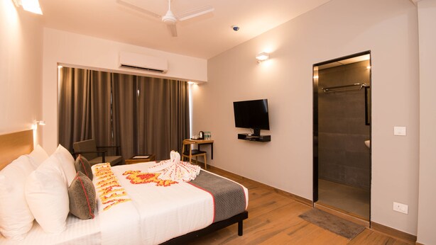 A hotel room with a bed, a television, an air conditioning unit, a shower, and a ceiling fan. - Hotel Vemara (Panaji)