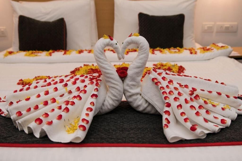 A bed with a white bedspread and pillows, a dark headboard, and a red accent at the foot of the bed.