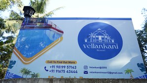 Une grande affiche publicitaire pour le complexe Vellankanni Resort, indiquant les coordonnées et présentant un décor tropical.