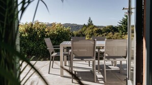 An outdoor patio with a table and chairs, surrounded by greenery and a view of hills. - Yewbeck: brand new, garden views (Cumbria)