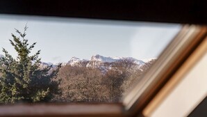 A view through a window with a mountain landscape, including snow-capped peaks and dense forest. - Yewbeck: brand new, garden views (Cumbria)