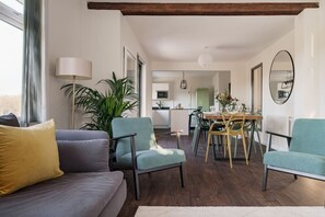 A living room with a sofa, chairs, a dining table, and a kitchen in the background. - Yewbeck: brand new, garden views (Cumbria)