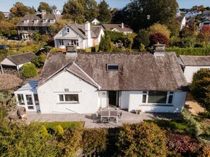A white house with a tiled patio, a small garden, and a view of neighboring houses. - Yewbeck: brand new, garden views (Cumbria)