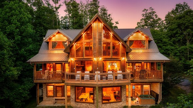 A large log cabin with multiple decks and a hot tub.