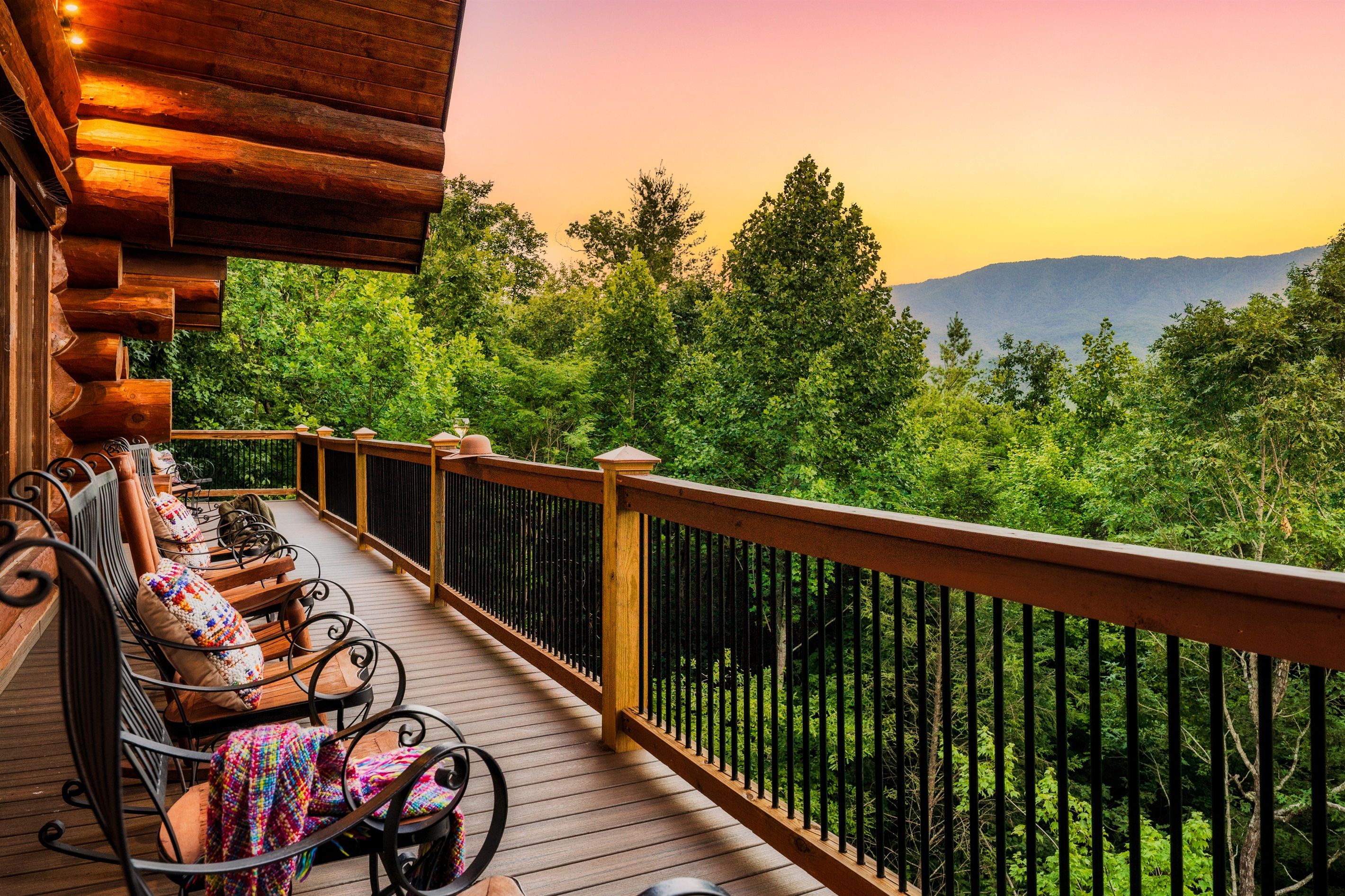Une terrasse en bois avec des sièges extérieurs, entourée d’une balustrade en bois, offrant une vue sur un paysage boisé.