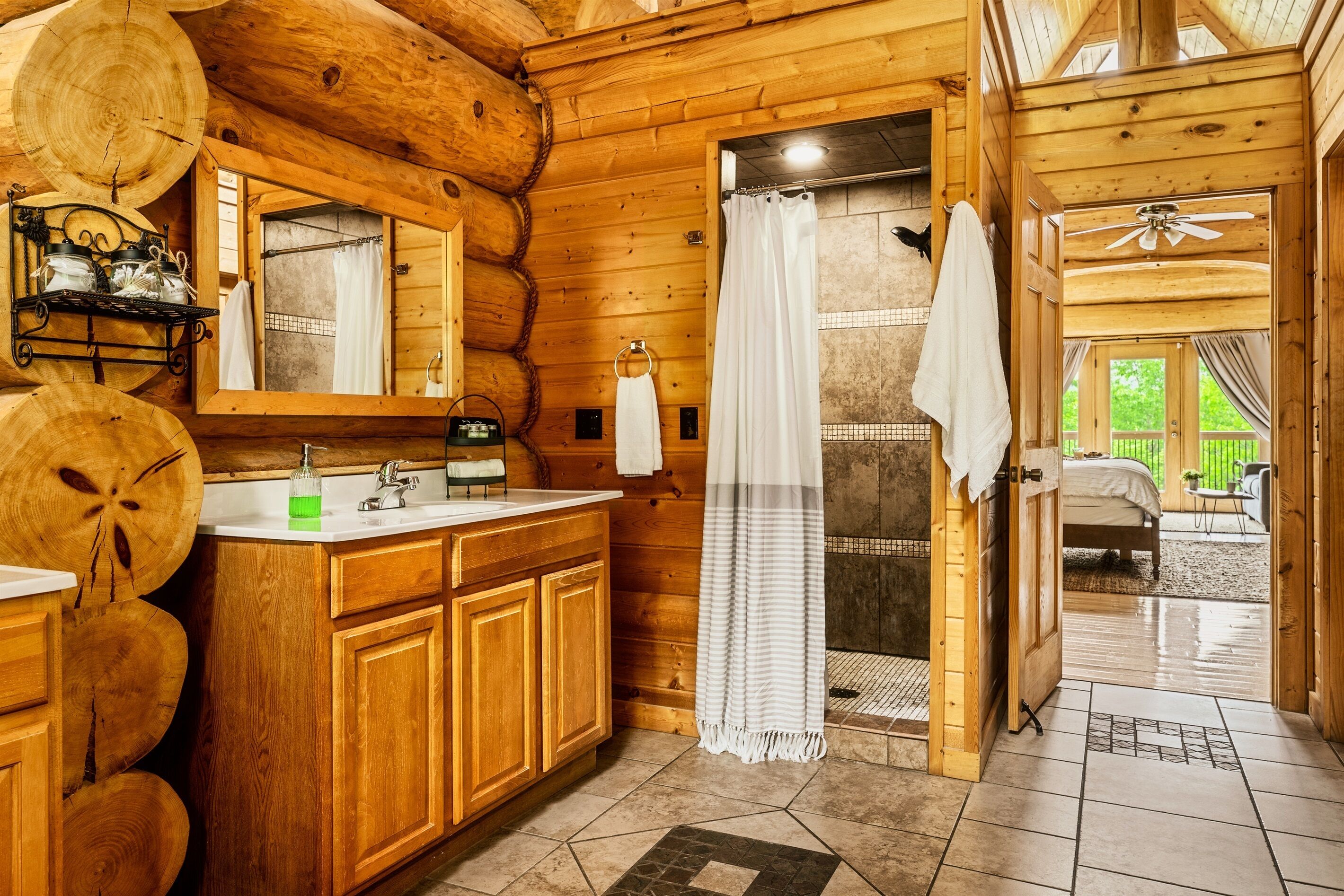 A wooden cabin bathroom with a sink, mirror, and shower area.