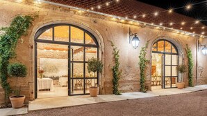 A building with arched windows, potted plants, and string lights. - Château de Veullerot, with its ponds in the heart of Burgundy (Liernais)