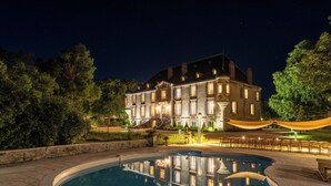 A large, illuminated building with a swimming pool in the foreground. - Château de Veullerot, with its ponds in the heart of Burgundy (Liernais)