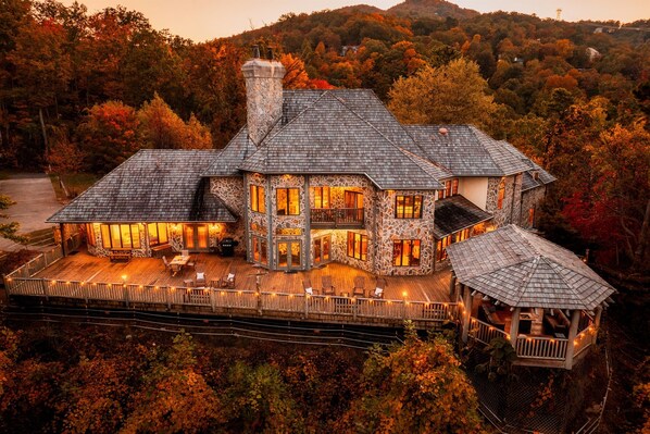 A large stone house with multiple levels, a covered deck, and a gazebo.