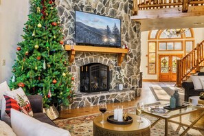 Una sala de estar acogedora con chimenea de piedra, un árbol de Navidad y un televisor montado encima.