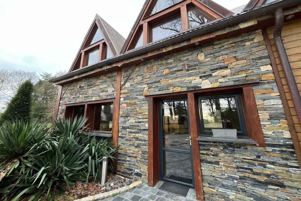 A stone building with a modern design, featuring a large glass door and windows.
