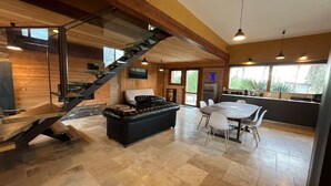 Een modern interieur met een trap, een zwarte leren bank, een eettafel met stoelen en een keukenhoek.