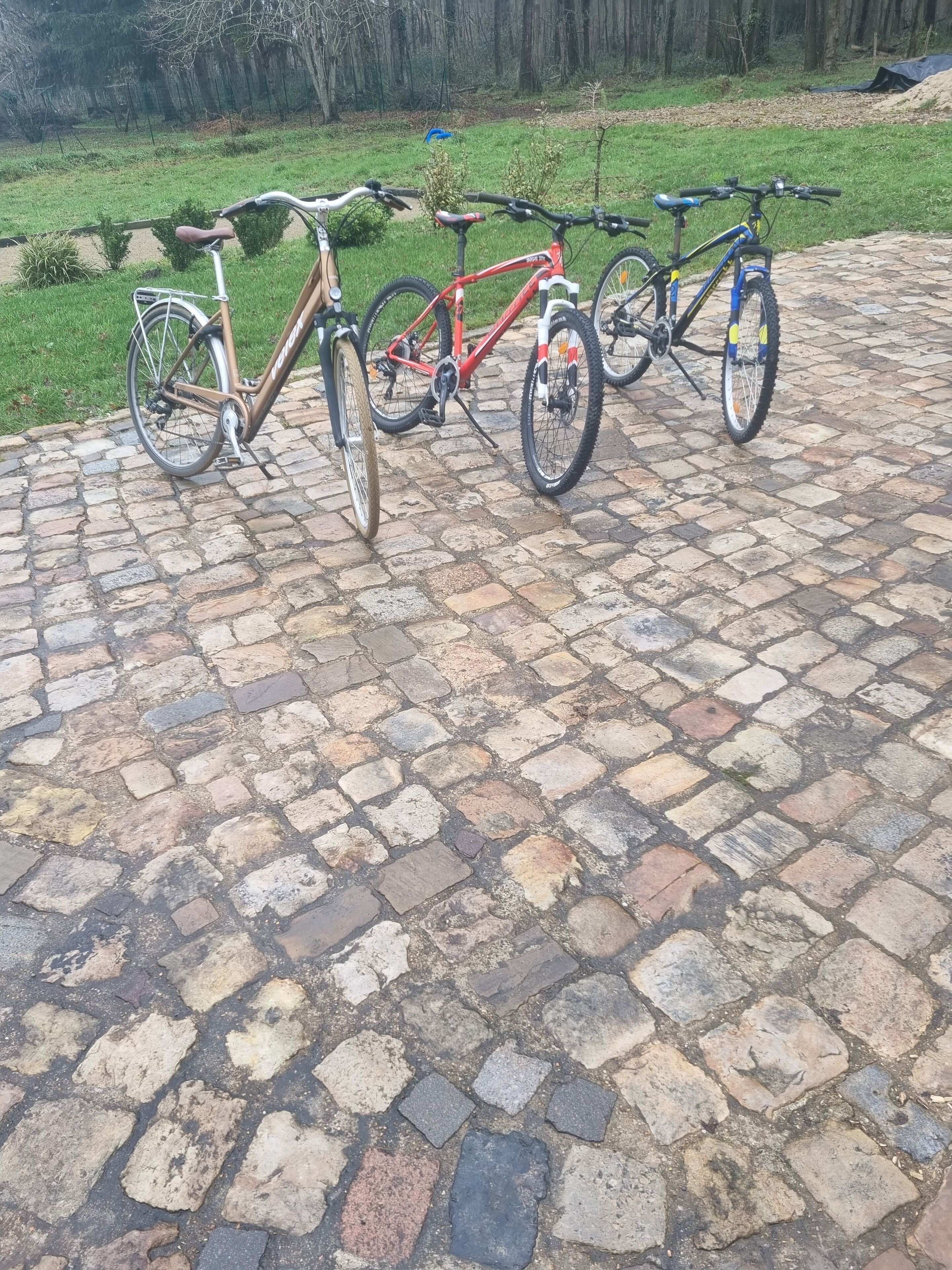 Tre cyklar parkerade på en kullerstensbelagd yta.