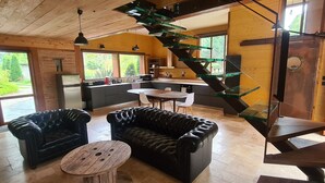 Een modern interieur met een leren bank, een ronde houten tafel en een glazen trap.
