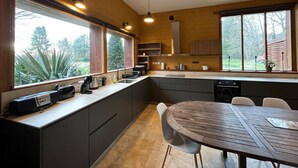 Een moderne keuken met een groot eiland, inbouwapparatuur en volop natuurlijk licht door grote ramen.