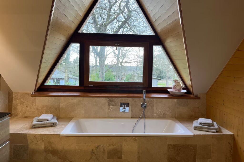 A bathroom with a bathtub, a window, and a view of trees.