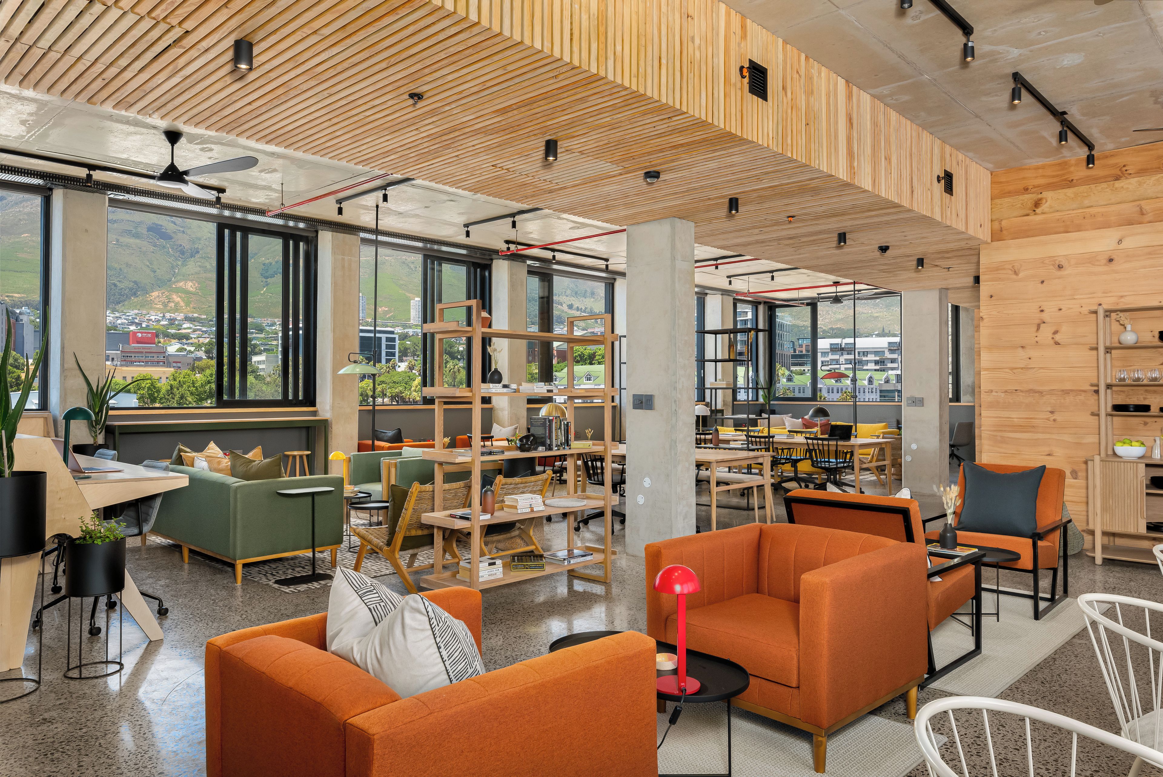 A modern library with wooden panel walls, large windows, and a variety of seating arrangements.