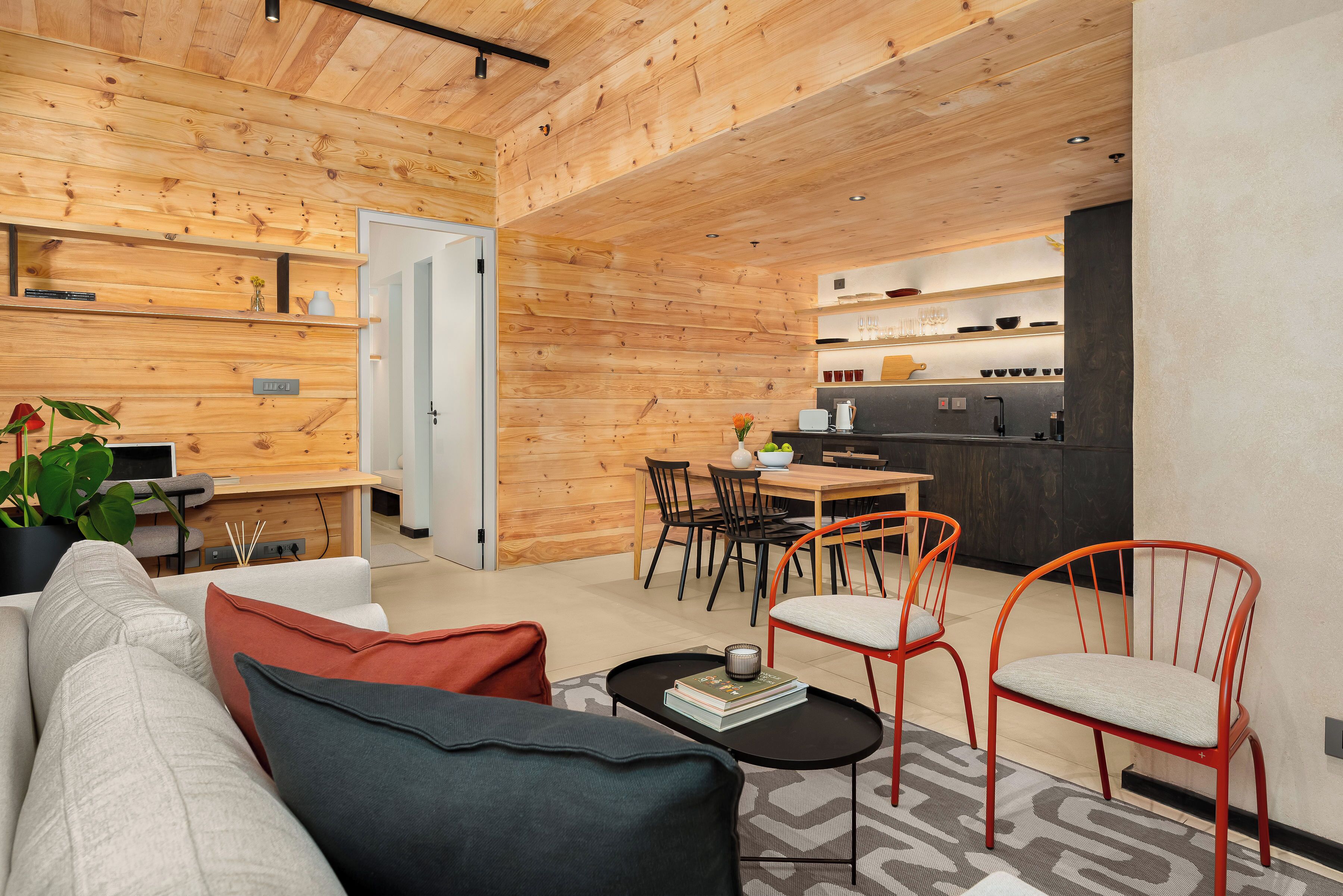 A modern interior with a wooden ceiling, a dining area with a table and chairs, and a living space with a sofa and a coffee table.
