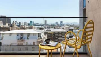 A balcony with a yellow chair and a small table, a book, and a cup.