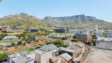 A cityscape with modern buildings, a parking lot, and a mountain in the background.