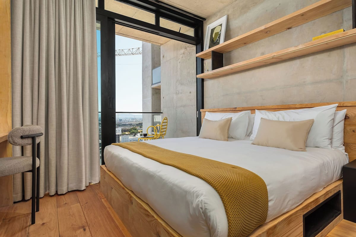 Un dormitorio moderno con una cama grande, cabecera de madera y vistas por la ventana.
