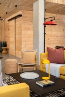 A modern interior with wooden walls, a yellow sofa, a black coffee table, and a red lamp.