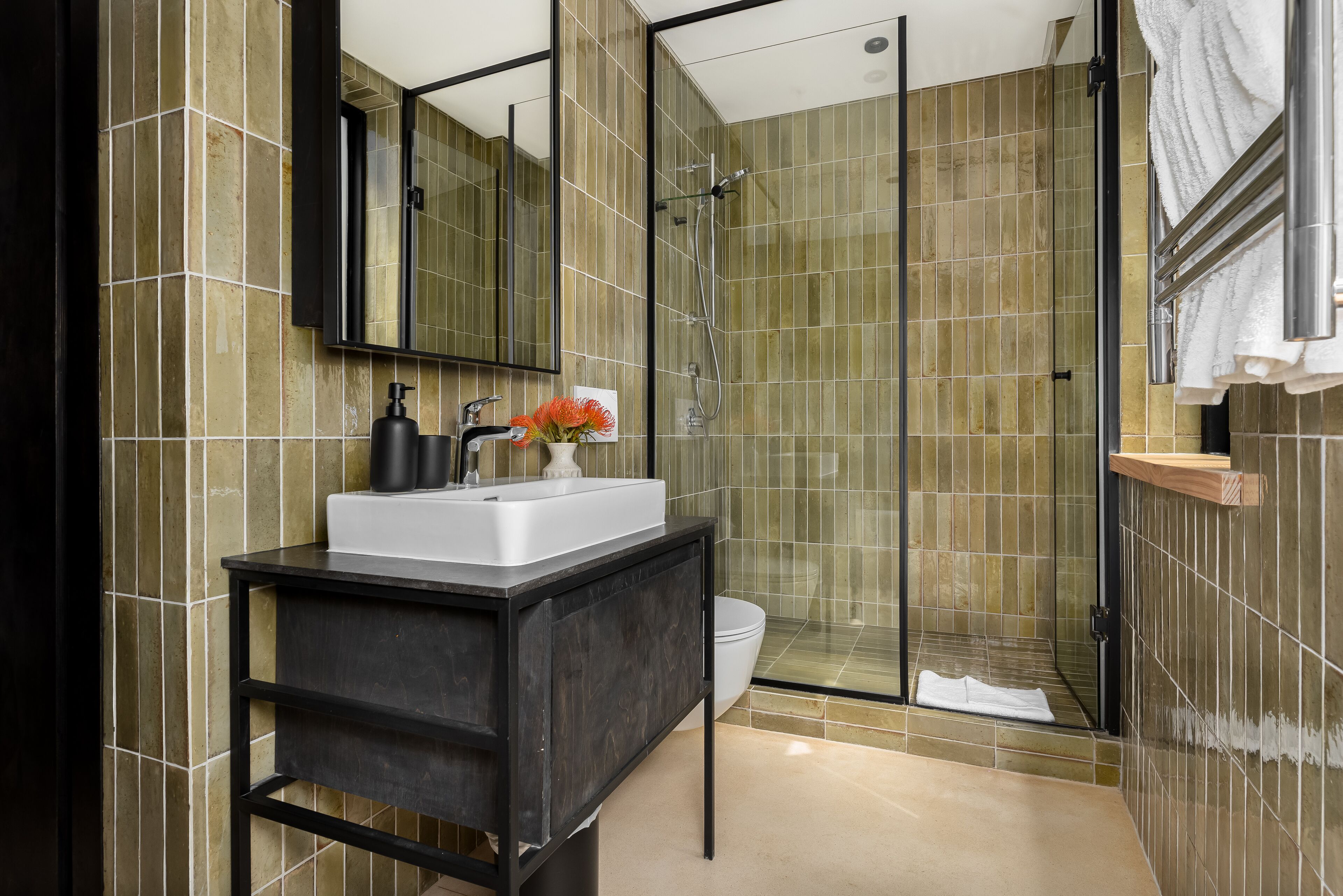 Een moderne badkamer met een douchecabine van glas, een zwart wastafelmeubel en een grote spiegel.