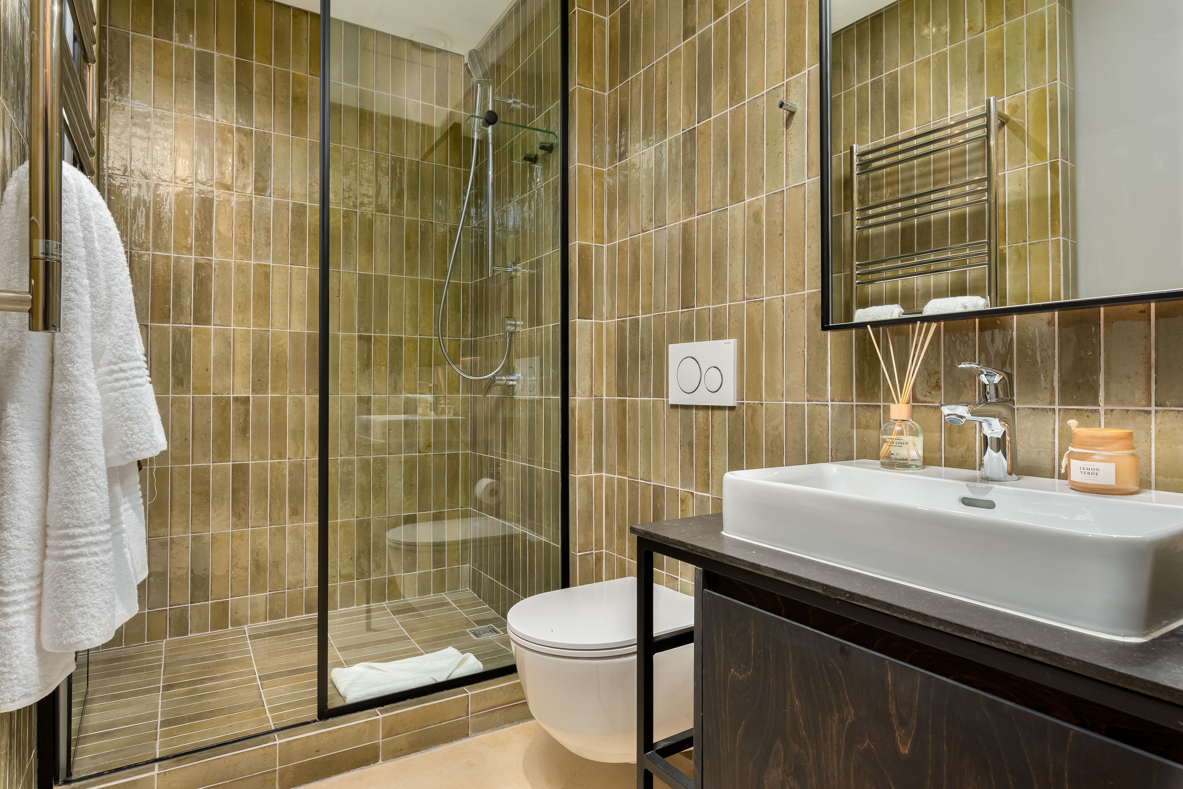 A modern bathroom with a glass shower enclosure, a white sink, and a mirror above it.