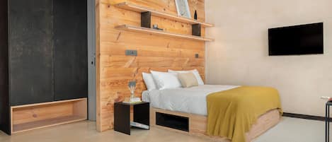 A modern bedroom with a bed, wooden shelves, a TV, and a wardrobe.