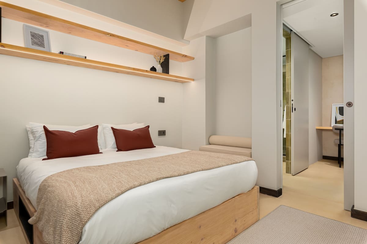 Un dormitorio moderno con una cama grande, cabecera de madera y estanterías empotradas.