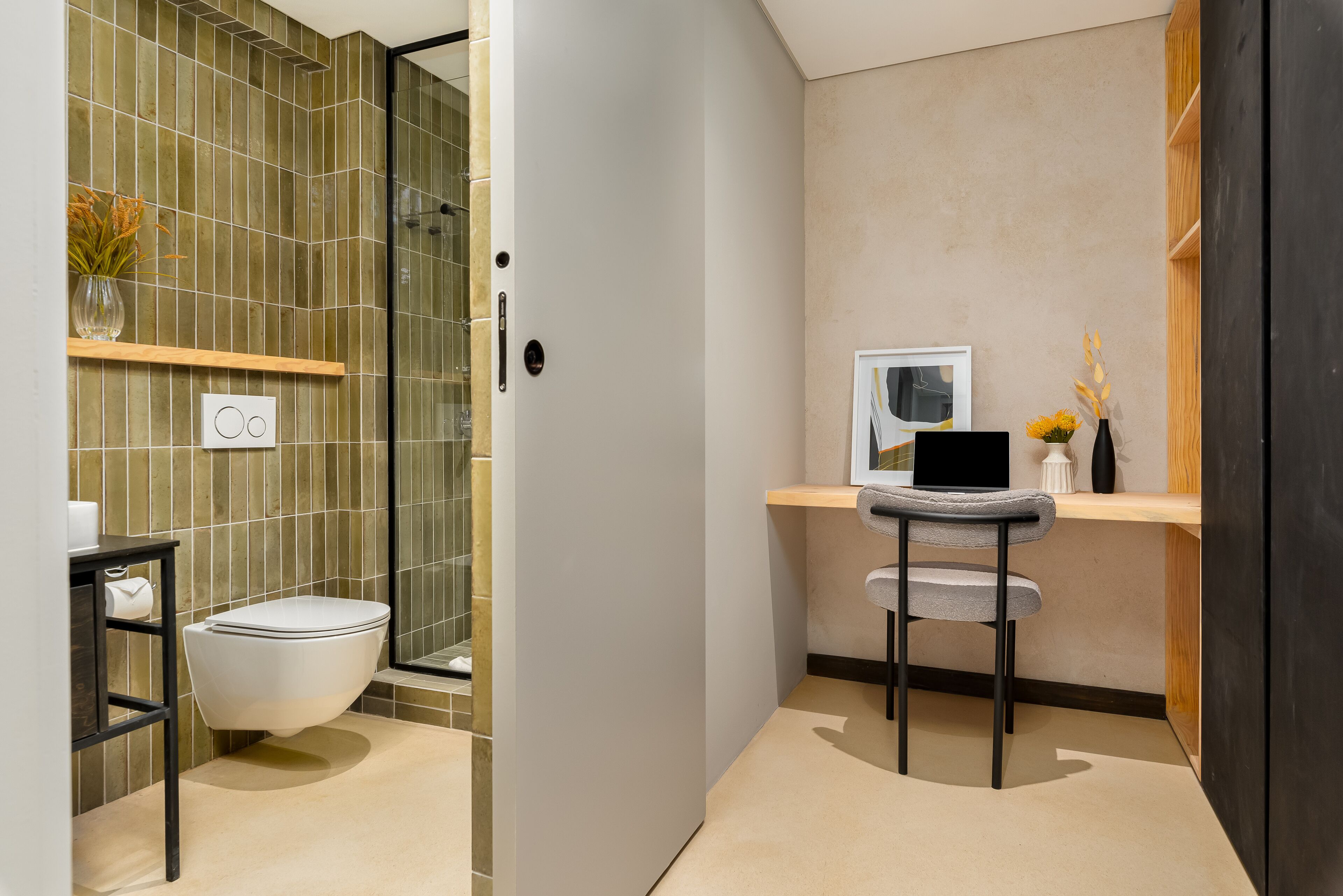 A modern bathroom with a toilet, shower, and a small desk with a chair.