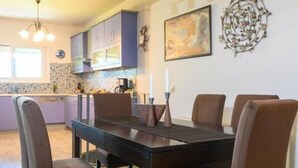 A modern kitchen with a dining table and chairs, a pendant light, and a decorative wall piece. - Crete Getaway 3Bd Apt w Garden and View (Malevizi)