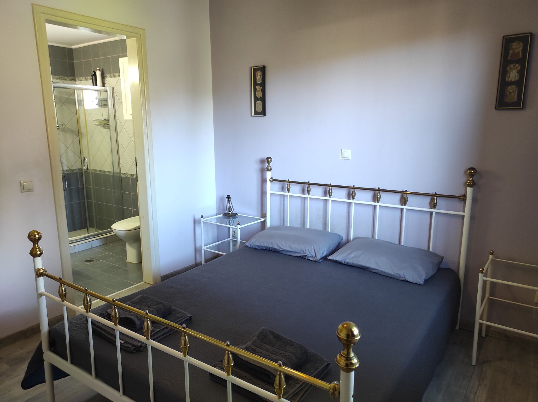 Une chambre à coucher comprenant un lit, des tables de chevet, un miroir et un espace douche.