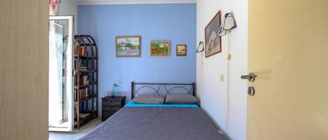 Une chambre à coucher avec un lit, une bibliothèque et une porte.