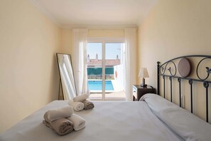 Ein Hotelzimmer mit Bett, Blick auf einen Swimmingpool und einem Metall-Kopfteil.