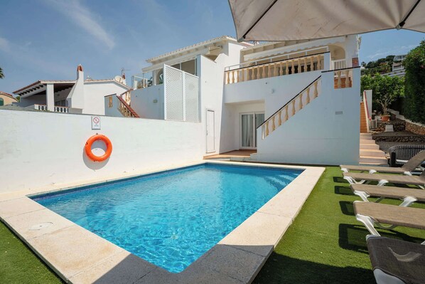 Ein Schwimmbecken mit Rettungsboje, einer Treppe und Gartenmöbeln.