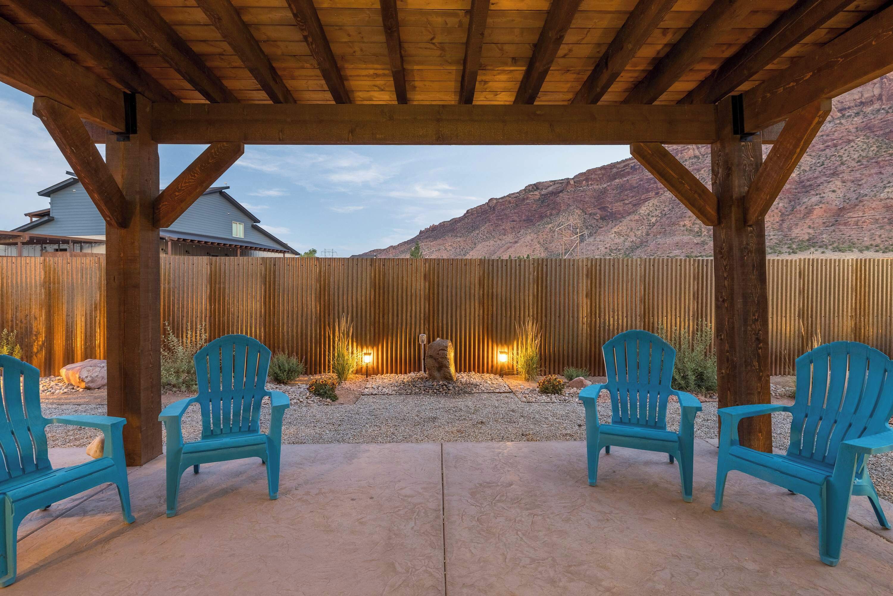 Un patio cubierto con dos sillas azules, una cerca de madera y vistas a la montaña.