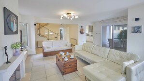 A spacious living area with a sofa, coffee table, and artwork on the walls. - Protaras Serifos Villa Sv07 (Paralimni)
