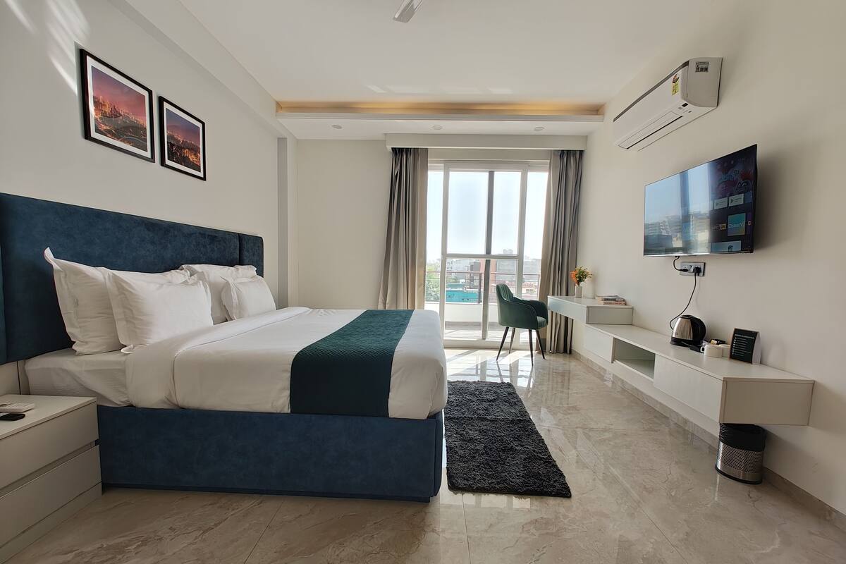 Ein modernes Hotelzimmer mit einem großen Bett, einem Schreibtisch, einem Stuhl, einem Fernseher und Blick auf die Stadt.