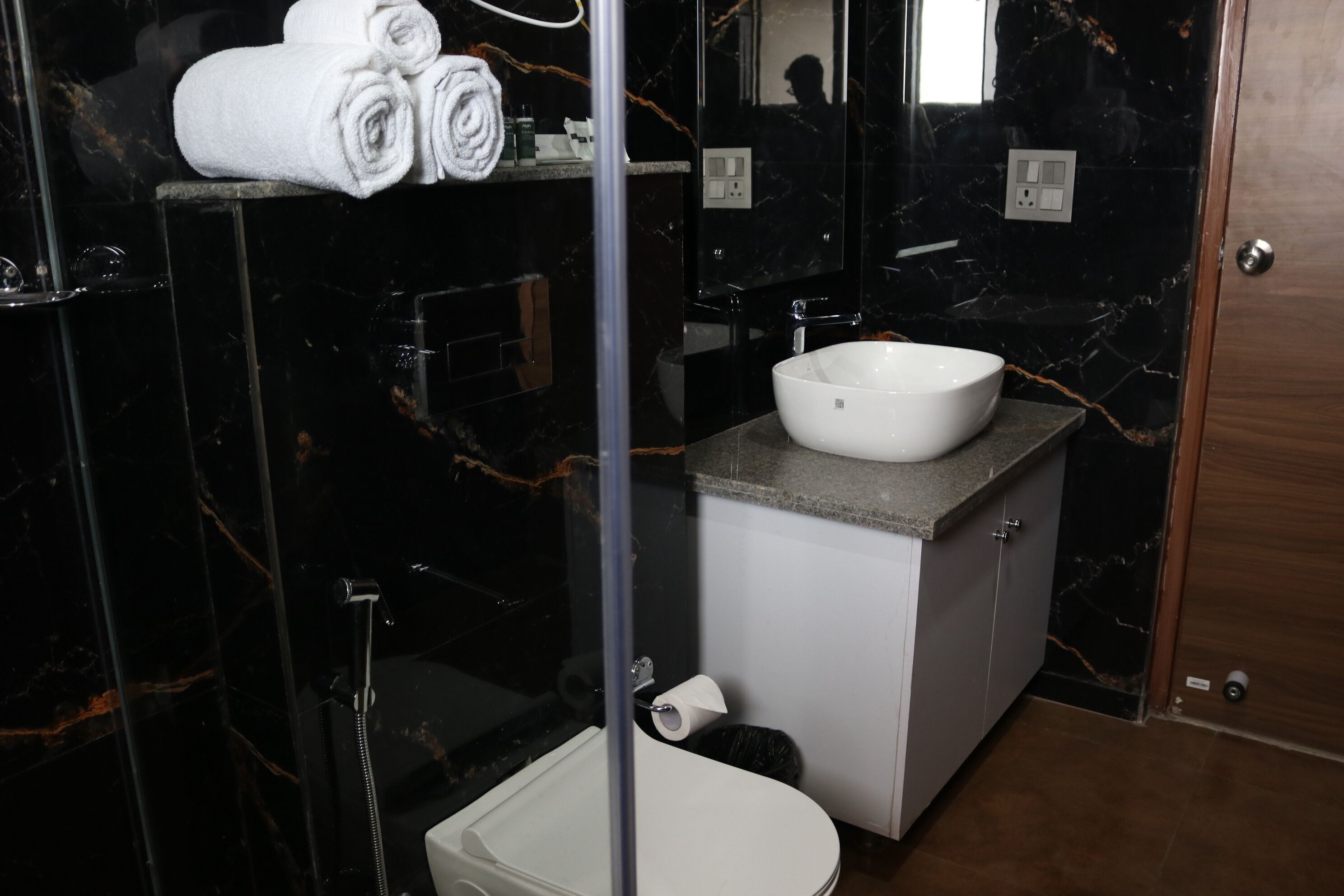 A modern bathroom with a marble vanity, a white sink, and a glass-enclosed shower.