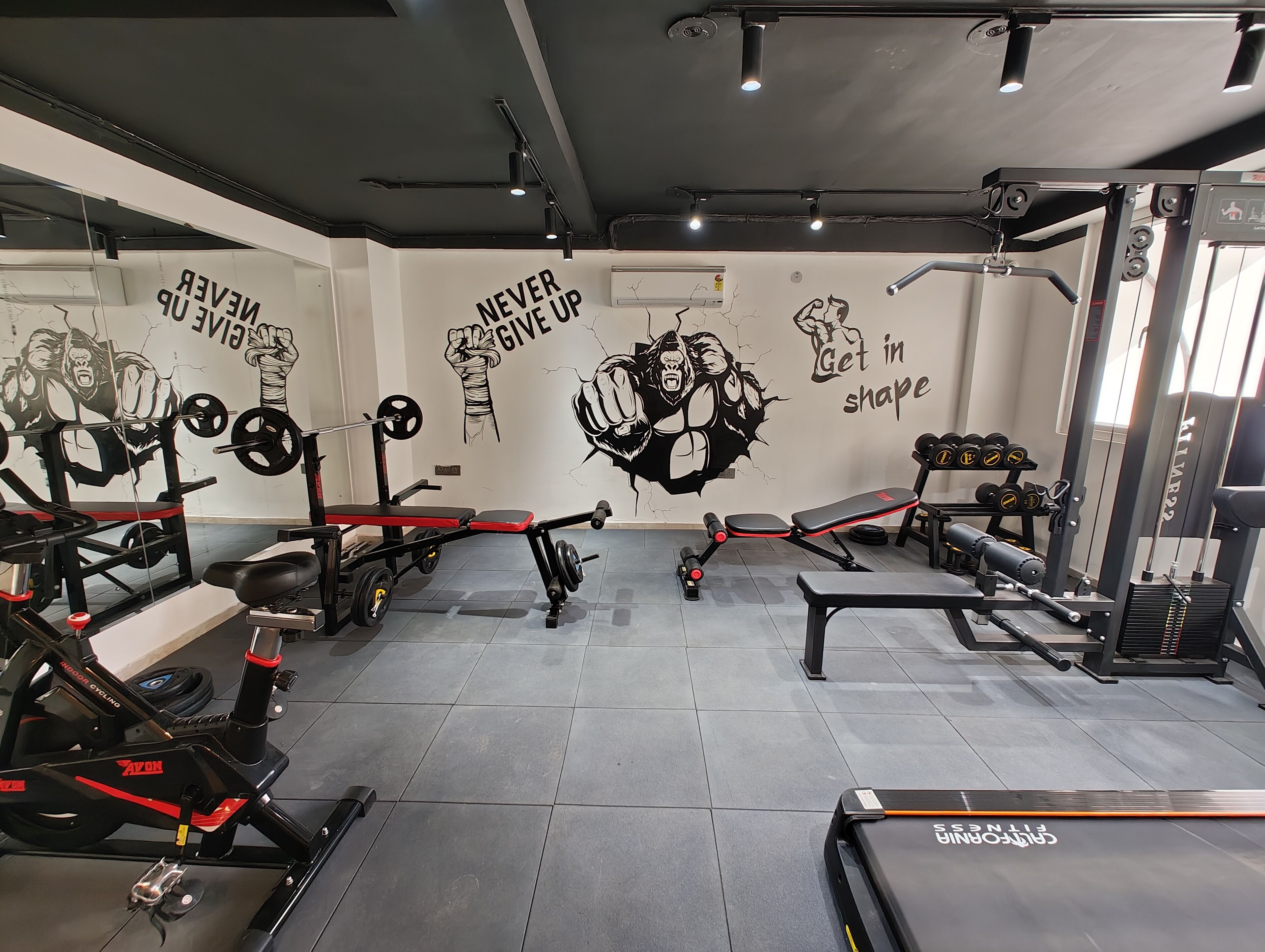 Een sportschool met diverse fitnessapparatuur, motiverende muurdecoratie en een schone, betegelde vloer.