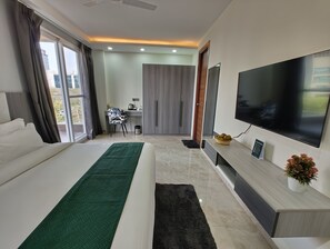 Relax in a serene space with a large bed, flat-screen TV, and desk area.